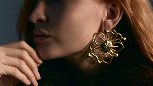 Woman wearing a gold earring with a dark background