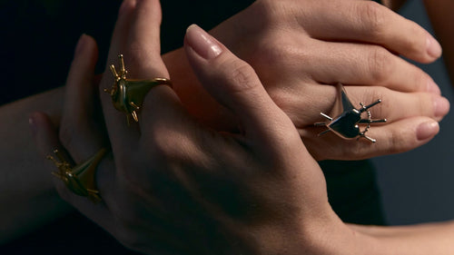 Close-up of hands wearing gold and silver rings with dark background