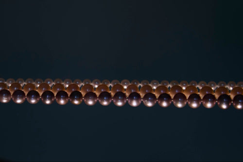Hand holding a string of pearls against a dark background
