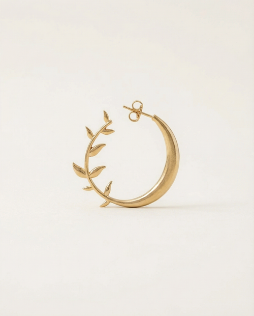Gold moon earring with leaf design on a light beige background