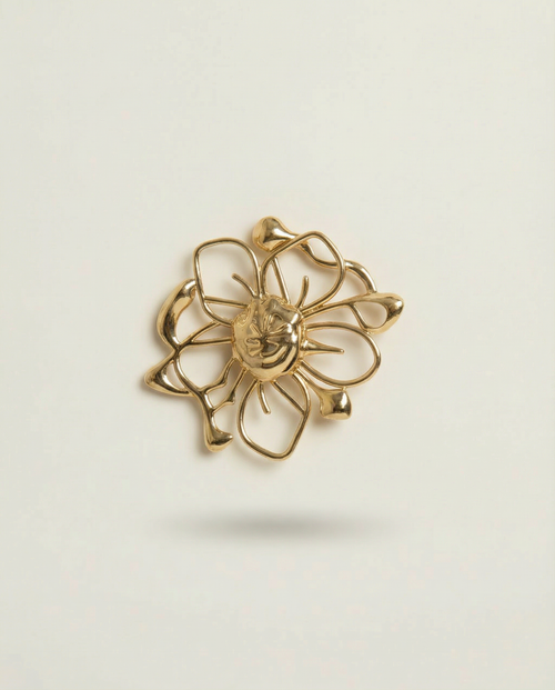 Gold floral earring on a light beige background