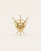 Gold heart-shaped ring with 3 swords on a light beige background