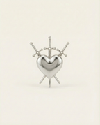 Silver heart-shaped ring with 3 swords design on a beige background